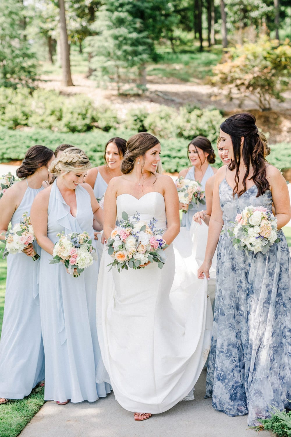 Bride and bridesmaids walk on sidewalk with flowers