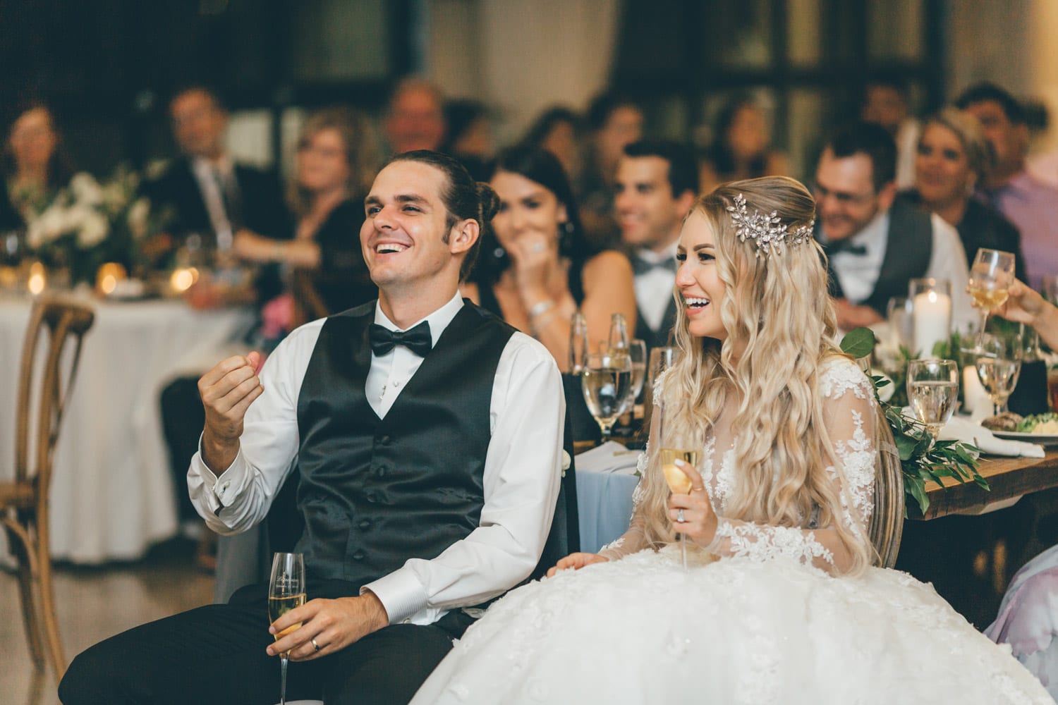 Bride and groom laugh together during dinner speech