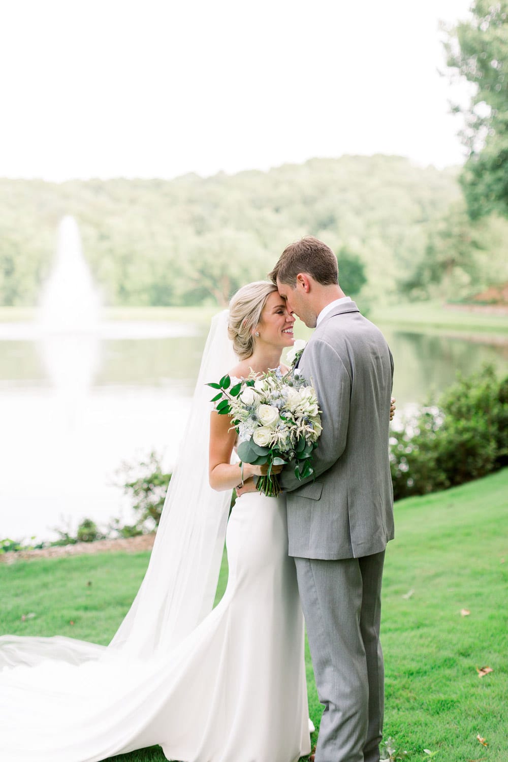 Bride and groom hold each other in front of fountain