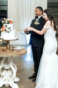 Bride and groom hold knife together as they cut their wedding cake at The Greystone Estate wedding venue