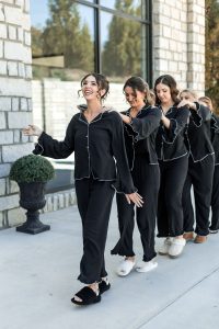 Bride and bridesmaids in pajamas holding each other walking in line and smiling at a north Georgia wedding venue