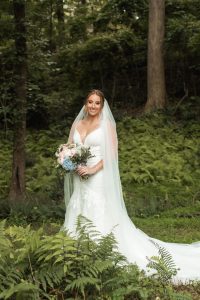 Bride holds flowers in wedding dress while posing in a fern forest at a north Georgia wedding venue