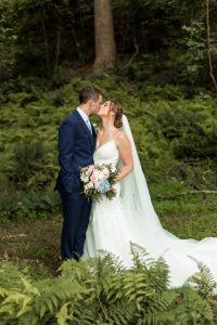 Bride and groom kiss each other while standing in a fern forest at a north Georgia wedding venue
