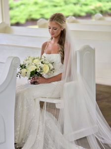 Bride holding flowers while sitting on white chapel pews at a north Georgia wedding venue