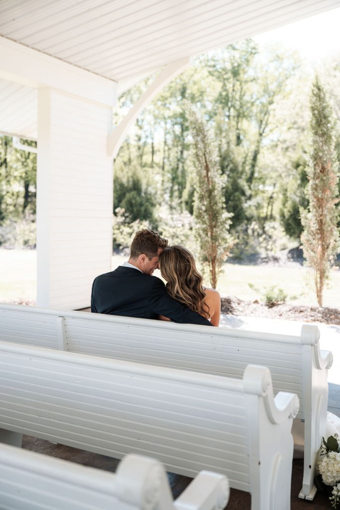 Bride and groom hold each other sitting under chapel at The Grand wedding venue in North Georgia